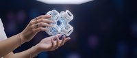Hands holding transparent gear mechanism against blurred dark background, representing technology, innovation, and business solutions for corporate presentations.