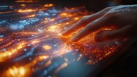 Glowing digital particles flow around human hand in futuristic technology visualization with orange and blue light effects creating magical atmosphere.