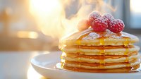 Stack of fluffy pancakes topped with fresh raspberries, maple syrup dripping down sides, dusted with powdered sugar, golden morning light background.