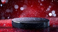 Hockey puck on red reflective surface with water drops and bokeh lights in background, dramatic sports equipment macro photography in dark setting.