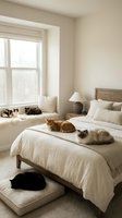 Cozy neutral bedroom with multiple cats relaxing on bed and window seat in warm natural light creating peaceful domestic atmosphere.
