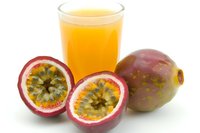 Passion fruit juice in glass with fresh whole and halved fruits on white background, ready for beverage, tropical drink, and healthy lifestyle design projects.