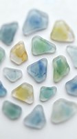 Polished sea glass stones in soft blue, green, and yellow hues arranged on white background. Frosted gemstone pieces ideal for jewelry design, craft projects, and wellness product marketing.