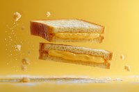 Floating grilled cheese sandwich with melted cheddar cut diagonally, sprinkled with powdered sugar against vibrant yellow background, dynamic food levitation photography.