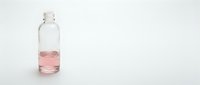 Young woman with South Asian ethnicity, wearing professional business attire, holding a clear glass bottle filled with pink liquid, isolated on white background for product mockup and packaging design use.