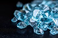 Sparkling blue crystal fragments scattered on dark background with selective focus creating dramatic lighting effect and luxurious gemstone appearance.