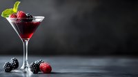 Red cocktail garnished with fresh raspberries, blackberries and mint leaves in martini glass on dark background with copy space for menu design.
