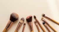 Professional rose gold makeup brush set with natural bristles arranged on neutral beige background for beauty and cosmetics applications.
