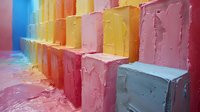 Colorful geometric steps in pastel rainbow colors with textured surface and rough edges create abstract architectural composition with soft lighting effects.