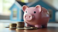 Pink ceramic piggy bank with stacked coins on wooden table against blurred background, representing savings, financial planning and money management concept.