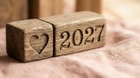 Wooden blocks with heart symbol and 2027 date carved on fabric surface, representing love, future planning, and new year celebrations.