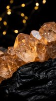 Golden citrine crystals on charcoal with warm bokeh lights creating mystical atmosphere for meditation, healing practices, and spiritual wellness concepts.