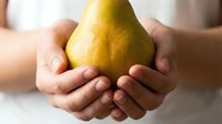 Fresh ripe pear held gently in cupped hands showcasing organic fruit harvest and healthy eating lifestyle for nutrition wellness concepts.