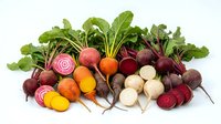 Fresh assorted root vegetables including red, golden and white beets with leafy greens isolated on white background for cooking, nutrition and healthy eating content.