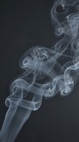 Swirling white smoke curls and twists against a dark background, creating elegant abstract shapes with soft flowing motion.