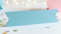 Blue ribbon banner on white surface with colorful confetti and bokeh lights creating festive party atmosphere for celebrations and events.
