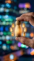 Hand holding wooden peg figures with glowing leader in center surrounded by team members against blurred colorful bokeh background for leadership and teamwork concepts.