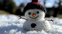 Handcrafted white crochet snowman with red hat and twig arms sitting in fresh snow, featuring charming button details and carrot nose, captured in soft winter light.