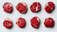 Eight raw beef steaks arranged in two rows on a white background, showcasing rich marbling and fresh red color for food and culinary use.