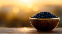 Fresh black caviar in wooden bowl against golden sunset background, luxury gourmet food styling with natural bokeh effect and warm lighting creates elegant atmosphere.