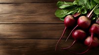 Fresh organic red beets with green leaves on rustic wooden background. Dark moody food photography with copy space for menu or recipe design.