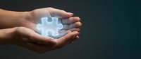Hands holding glowing puzzle piece symbolizing solution, teamwork and problem solving in business concept with copy space for text design.