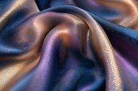 Luxurious silk fabric with shimmering gold and purple iridescent texture, elegant waves and folds creating dramatic light effects and sparkles on smooth surface.