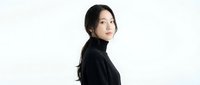 Young Asian woman in black turtleneck sweater looking over shoulder with confident expression on white background for fashion and lifestyle projects.
