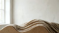 Abstract wavy cardboard layers creating flowing sculptural forms in minimalist interior with natural window light and neutral tones for modern design.
