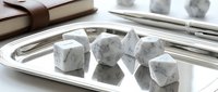 Polished white marble stone cubes arranged on silver tray with leather journal and sketches, suitable for interior design and luxury home decor projects.