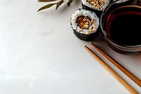 Fresh sushi rolls with sesame seeds served with soy sauce in ceramic bowl and bamboo chopsticks on white background, top view with copy space.