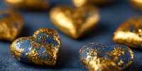 Golden heart-shaped decorative elements with glittering texture arranged on dark blue background for luxury design projects.