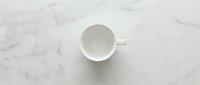 Empty white ceramic cup on marble surface, overhead view, minimalist design for beverage, kitchen, and lifestyle projects.
