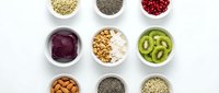 Healthy superfood ingredients in white bowls arranged in grid pattern on clean background for nutrition and wellness concepts.