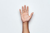 Raised open palm of young Asian person showing five fingers against white background, minimal composition for business and communication concepts.