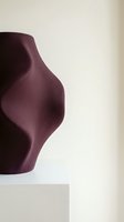 Modern burgundy ceramic vase with organic curved silhouette against neutral background for contemporary home decor and interior design projects.