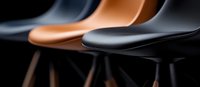 Modern dining chairs in black and tan leather with wooden legs arranged in row against dark background, minimalist furniture design with selective focus.