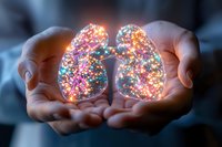 Glowing multicolored lights forming lung shape held in cupped hands against dark background, representing breath, life force and healing energy in medical concept.
