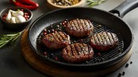 Juicy grilled beef medallions with grill marks in cast iron pan, garnished with rosemary sprigs and peppercorns. Dark moody food photography.
