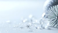 Silver Christmas ornament with sparkling snowflakes on white glittery background for holiday decorations and seasonal greeting cards.