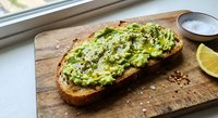 Fresh avocado toast on rustic bread with herbs and lime, healthy breakfast meal on wooden cutting board near window for food blogs and restaurant menus.