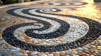 Spiral pattern made from black and white pebbles on garden path creates mesmerizing design catching golden sunlight, decorative mosaic walkway for landscaping.
