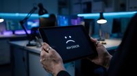 Close-up of hands holding tablet with 404 error message in modern office workspace with neon blue and purple lighting at night.
