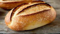 Fresh baked artisan bread loaves with golden crust on rustic wooden surface. Homemade bakery products for breakfast, sandwich making and culinary use.