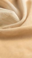Soft beige fabric with flowing folds and gentle curves creating elegant textile waves. Luxurious material texture for fashion and interior design projects.