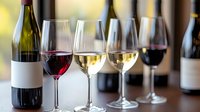 Wine glasses filled with red and white varieties arranged for tasting, with unlabeled bottles in background creating elegant composition against soft bokeh lighting.