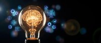Glowing light bulb with brain filament surrounded by digital technology icons on dark background representing innovation and artificial intelligence concepts.