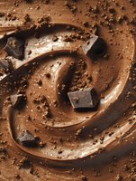 Swirling chocolate cream texture with dark chocolate pieces and crumbs creating luxurious dessert background. Macro food photography for confectionery advertising.
