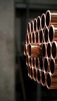 Stack of shiny copper pipes arranged in rows at industrial warehouse facility for plumbing and construction projects with selective focus depth of field.