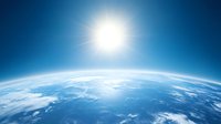 Curved horizon of planet Earth viewed from space with bright sun rising over blue atmosphere and white clouds covering surface. Suitable for environmental themes.